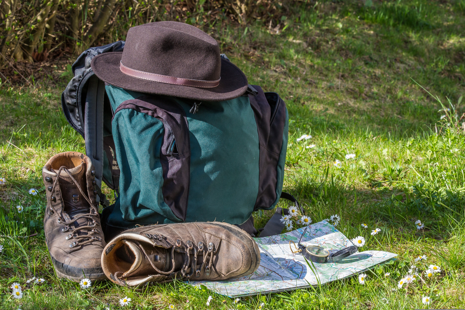 Wanderrucksack mit Schuhen und Karte auf einer Wiese